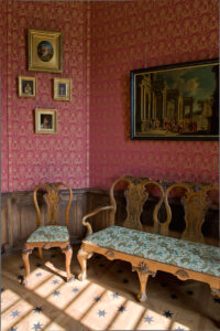 pokój ze stołem i krzesłami, na ścianach wiszą obrazy