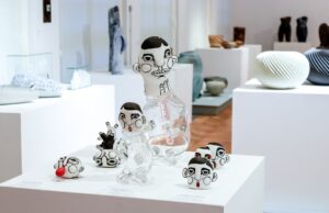 Ceramiczne figurki małych postaci ludzkich z głowami umiejscowionymi w szklanych naczyniach w kształcie słoików z nóżkami i rękami oraz same głowy bez korpusu autorstwa Janiny Myronovej
