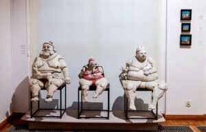 Trzy siedzące postacie ceramiczne w strojach kąpielowych i czepkach autorstwa Karoliny Krawczyk
