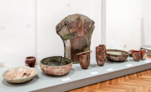 Część ekspozycji przedstawiająca wolnostojące figury ceramiczne w kształcie mis, wazonów i noża oraz stojącej centralnie ceramicznej figury o wachlarzowym przekroju autorstwa Grażyny Płocicy