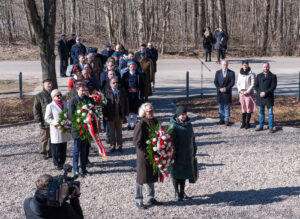 grupa ludzi składająca kwiaty pod pomnikiem Józefa Wybckiego