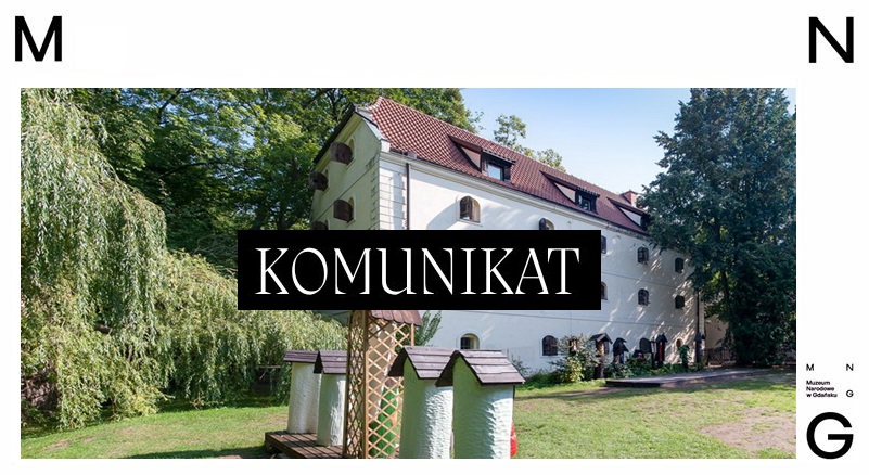 napis komunikat na tle budynku etnograficznego i uli